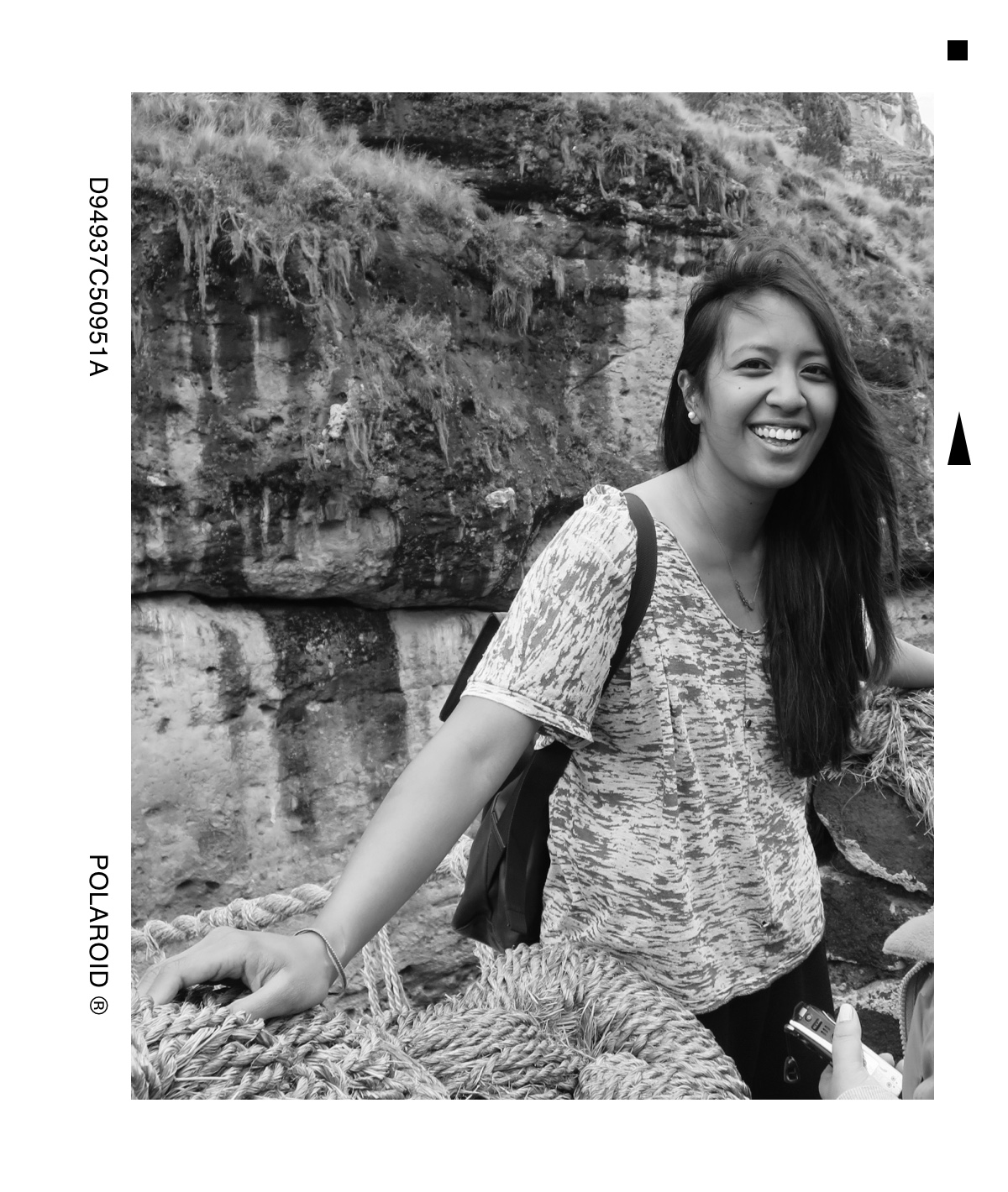 A picture of Gillian smiling in front of the Q’eswachaka Rope Bridge in Peru, made from weaved grass